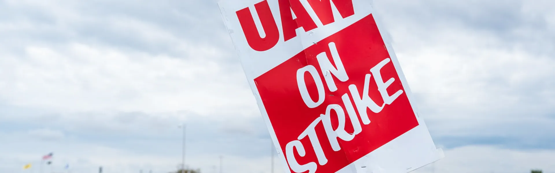 Bild på folk på strejk med en person som håller upp en skylt med texten "UAW on strike"