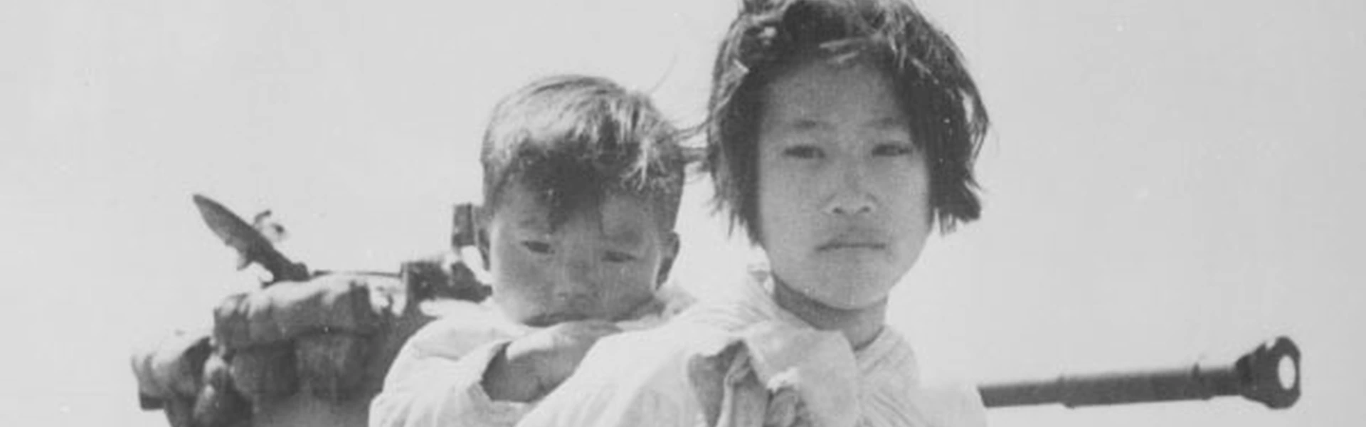 Korensk kvinna med barn framf&ouml;r en stridsvagn.