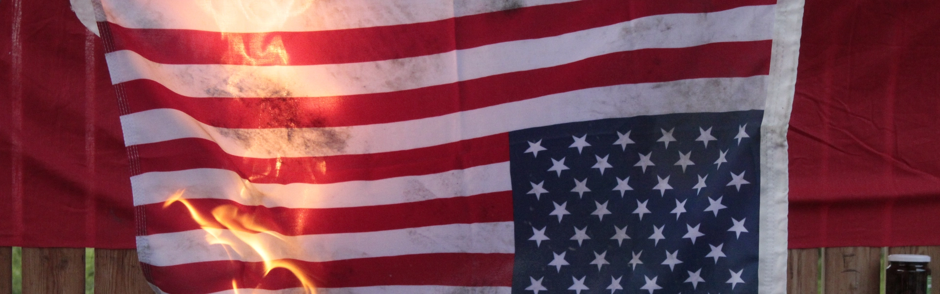 En USA flagga som h&auml;nger upp och ner brinner.